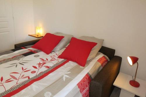 um quarto com uma cama com almofadas vermelhas em Studio au coeur de Saint Quentin en Yvelines em Trappes