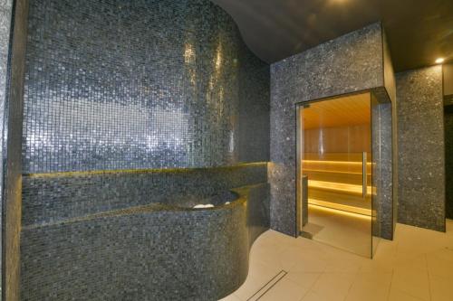 baño con ducha a ras de suelo y pared de azulejos en Polanki Aqua Apartament FLORA en Kołobrzeg