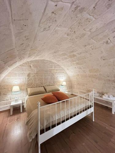 ジョヴィナッツォにあるGigò Homeの白いベッドと石の壁が備わるベッドルーム1室