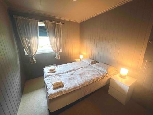 ein Schlafzimmer mit einem Bett mit zwei Lampen und einem Fenster in der Unterkunft Apartment-B near Etne-Odda in Etnesjøen
