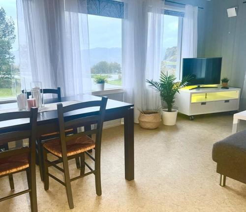 a dining room with a table and chairs and a tv at Apartment-B near Etne-Odda in Etnesjøen
