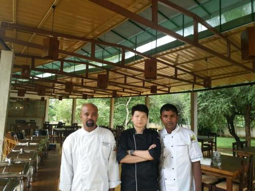 a group of three men standing in a restaurant at Eighth Wonder Resort in Sigiriya