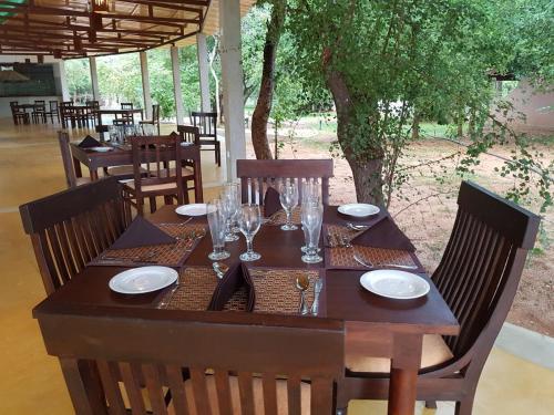 a wooden table with glasses and plates on it at Eighth Wonder Resort in Sigiriya
