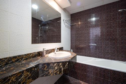 a bathroom with a sink and a tub and a mirror at Luxury and spacious full Marina view in Dubai