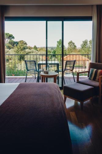 a room with a bed and a balcony with a view at Madre de Água Hotel Rural de Charme in Gouveia