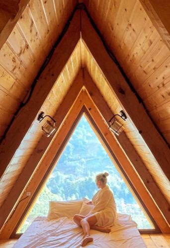 a man sitting on a bed in a room with a window at Eco cottage sunrise merisi in Merisi