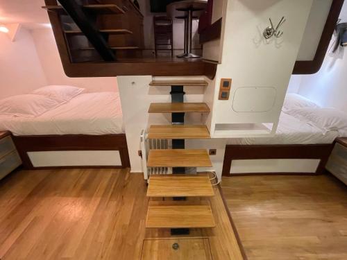 - une petite chambre avec 2 lits et un escalier dans l'établissement Cabine sur péniche à Bagatelle, à Paris