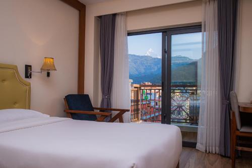 ポカラにあるHotel Fewa Tripのベッドと大きな窓が備わるホテルルームです。