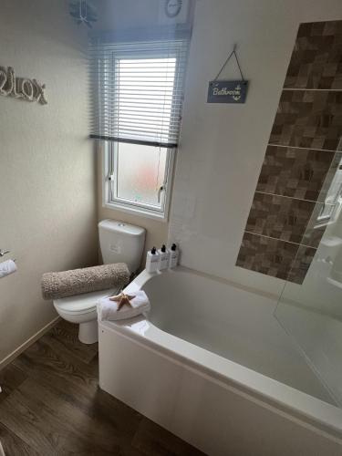 a bathroom with a tub and a toilet and a window at 2 Bed Caravan - Sleeps 6 - Parking - Pets in Whitley Bay