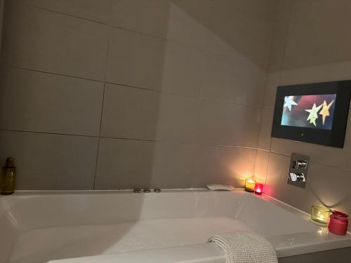 uma banheira branca na casa de banho com uma televisão em The Little Beech Tree em Linlithgow