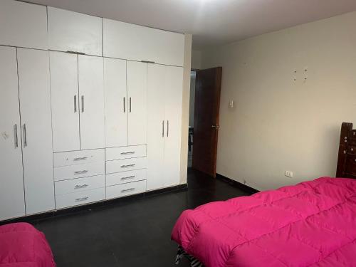 um quarto com armários brancos e uma cama rosa em Departamento en playa San Bartolo - cuarto piso em San Bartolo