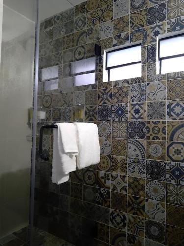 a bathroom with a shower with towels and tiles at Añoranza Hotel Boutique in Ciudad Hidalgo