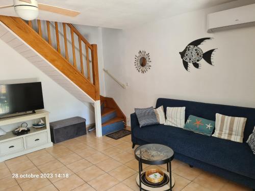 een woonkamer met een blauwe bank en een trap bij Villa tout confort dans résidence privée avec piscine à 500m de la plage - Climatisation, WIFI, parking in Portiragnes