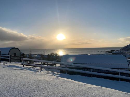 a snow covered fence with the sun rising over the ocean at Dunbeath Coastal Retreat in Dunbeath