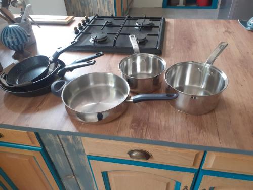 three metal pots and pans on a kitchen counter at L'Ancienne Colonie - maison conviviale au bord de la Gazeille - 8 pers in Le Monastier sur Gazeille