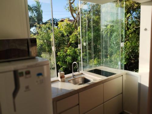 a kitchen with a sink and a large window at Pousada Ilha do Campeche in Florianópolis