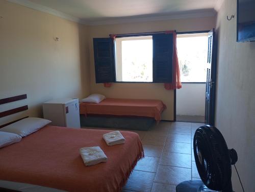 a room with two beds and a chair and two windows at Pousada e Pizzaria Sol e Alegria in Fortaleza