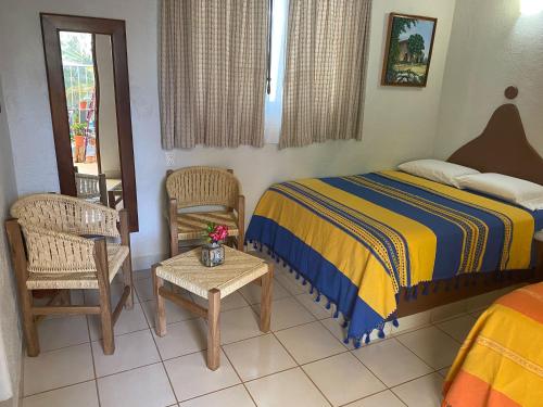 a bedroom with a bed and two chairs and a table at Zandoyo Bed & Breakfast in Puerto Escondido