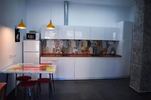 una cocina con armarios blancos y una mesa con taburetes en Sevilla Urban Flat, en Sevilla