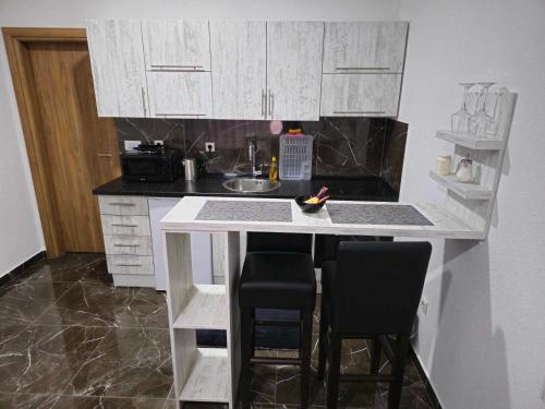 a kitchen with white cabinets and a counter with two bar stools at MALM Travnik in Travnik
