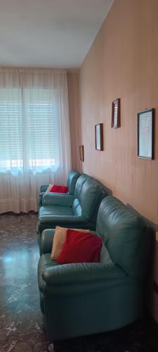 a living room with green leather couches and a window at Affittacamere Pratello 97 in Bologna
