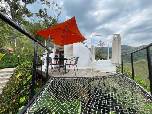 einen Balkon mit einem Tisch und einem Sonnenschirm in der Unterkunft GLAMPING LA CRISTALINA in Jamundí