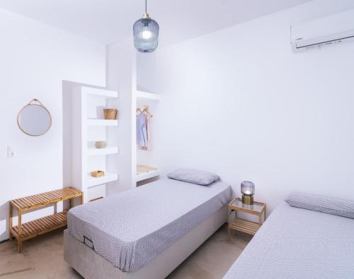 a white bedroom with two beds and a shelf at Nikkon summer house in Matala