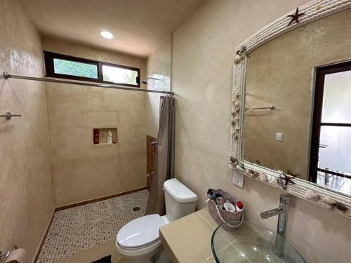 bagno con servizi igienici, lavandino e specchio di Luigi’s Glamping a Bacalar