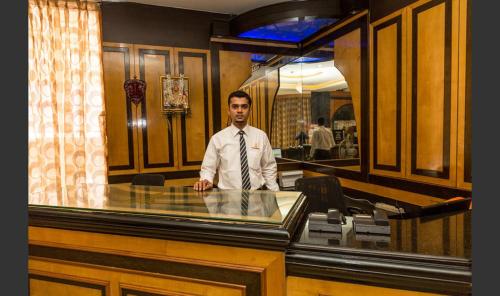 a man in a tie standing behind a glass counter at Hotel Sri Ram Residency in Udupi