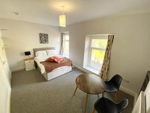 a bedroom with a bed and a table and a window at Budget Room Share facilities R3 in Swansea
