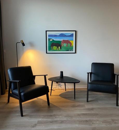 two chairs and a table in a room with a picture of horses at Hafnir in Grundarfjordur