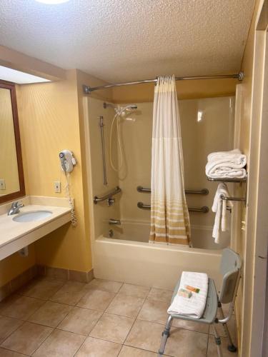 Un baño con bañera, lavabo y ducha. en Home Town Inn & Suites, en Crestview