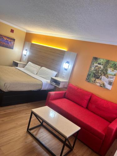 a hotel room with a bed and a red couch at Home Town Inn & Suites in Crestview