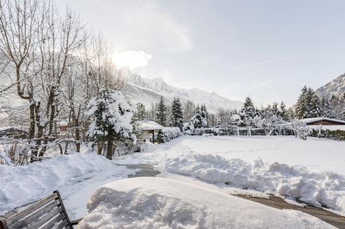 un parque cubierto de nieve con un banco y árboles en Spectacular Chalet with 5 ensuite bedrooms and sauna, en Chamonix-Mont-Blanc