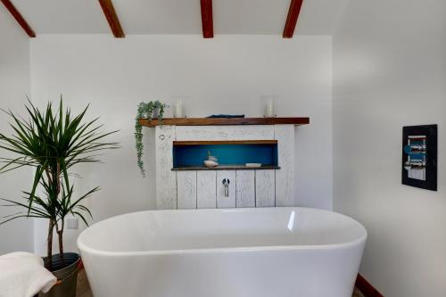 a white bath tub in a room with a plant at The Owl Barn Wiltshire - Sarsen in Swindon