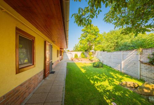 a house with a walkway next to a yard at Zöld dió Vendégház in Mezőkövesd