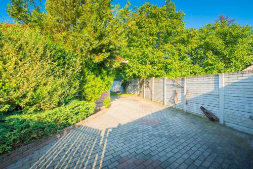a brick sidewalk next to a fence and trees at Zöld dió Vendégház in Mezőkövesd