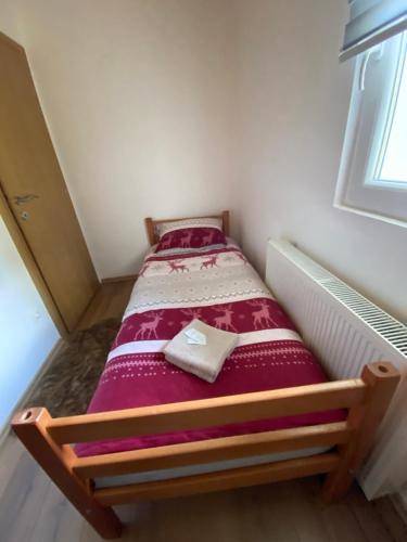 a small bed sitting in a room with a window at Apartmani Snježna Kraljica Vlašić 1 in Vlasic