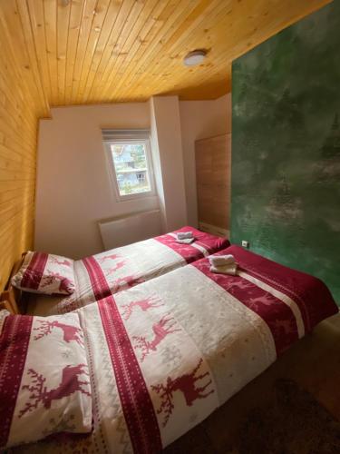 a bedroom with a bed with a red and white comforter at Apartmani Snježna Kraljica Vlašić 1 in Vlasic