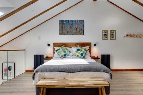 斯溫頓的住宿－The Owl Barn Wiltshire - Sarsen，一间卧室配有一张大床和一张木桌