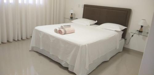 Una cama blanca con dos toallas encima. en Apartamento no centro próximo a Jk, en Palmas