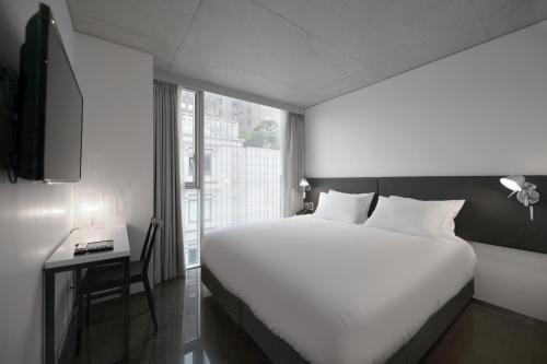 a bedroom with a large white bed and a window at Creto Hotel Myeongdong in Seoul