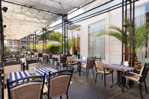 ein Restaurant mit Tischen, Stühlen und Fenstern in der Unterkunft Rome Palace Deluxe - All Inclusive in Sonnenstrand
