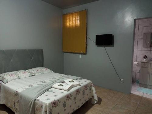 a bedroom with a bed and a television in a room at Apto Confortável e espaçoso 01 in Cachoeira do Sul