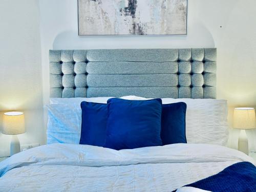 Bett mit blauem Kopfteil in einem Schlafzimmer in der Unterkunft Sutton - Ground Floor Flat By The High Street in Sutton