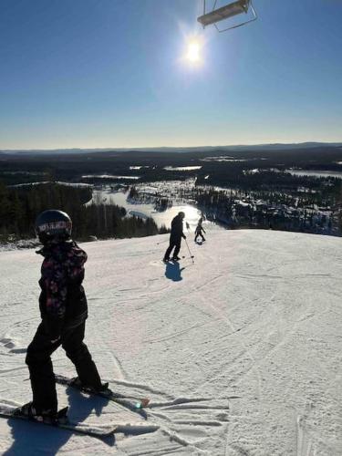 two people are skiing down a snow covered slope at Loft ”Aurora” Ski Resort in Kåbdalis