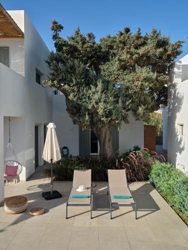 two chairs and a table and a tree at Private Luxury Scarlet beachfront villa, Molos, Paros in Molos Parou