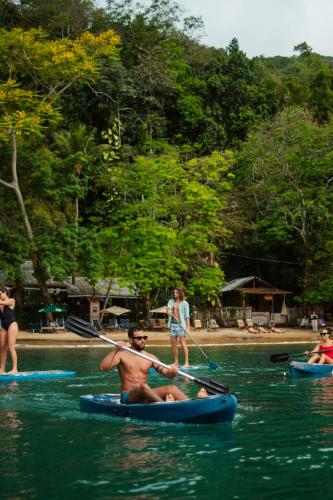 a man in a paddle boat on a river at Bonito Paraiso Ilha Grande in Abraão