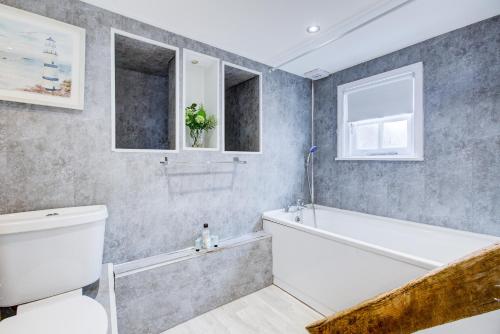 a bathroom with a white tub and a toilet at Spacious One Bedroom Apartment in The Heart Of Brentwood in Brentwood
