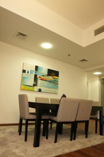 un comedor con mesa, sillas y una pintura en Shams JBR Hostel, en Dubái